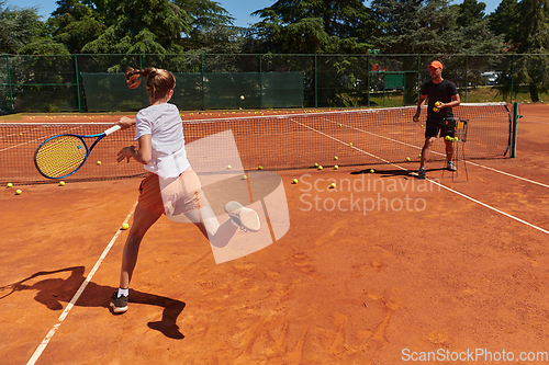 Image of A professional tennis player and her coach training on a sunny day at the tennis court. Training and preparation of a professional tennis player