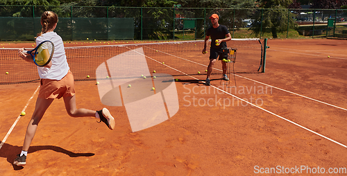 Image of A professional tennis player and her coach training on a sunny day at the tennis court. Training and preparation of a professional tennis player