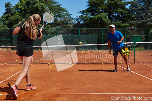 Image of A professional tennis player and her coach training on a sunny day at the tennis court. Training and preparation of a professional tennis player