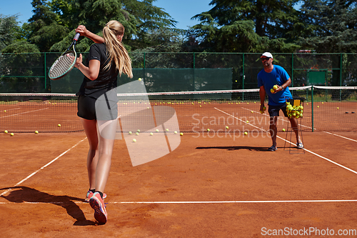 Image of A professional tennis player and her coach training on a sunny day at the tennis court. Training and preparation of a professional tennis player