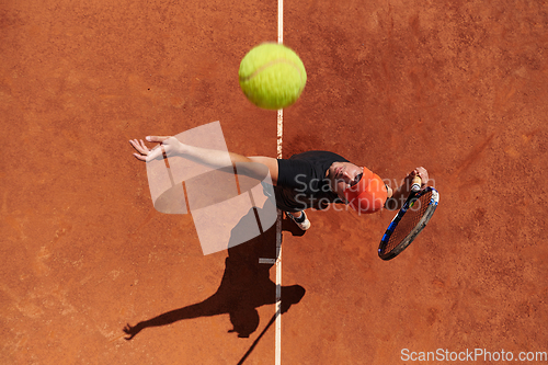 Image of Top view of a professional tennis player serves the tennis ball on the court with precision and power