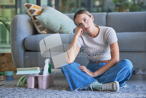 Image of Woman, tired and stress for cleaning house sitting on floor with exhausted look on face. Girl, working and burnout in home living room with headache with soap, spray and brush for domestic work