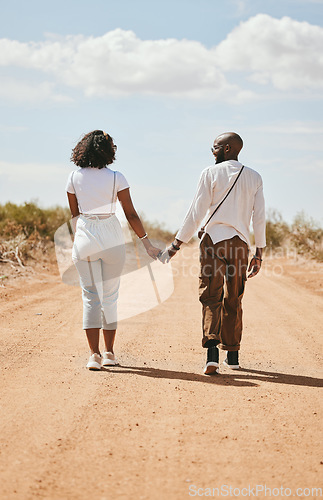 Image of Black couple, love and holding hands back view in nature walking on vacation on desert, sand or dirt road. Romance, safari and man, woman and bonding, care or spending time together on outdoors date.