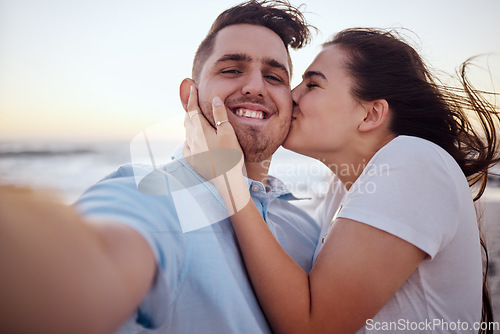 Image of Selfie, beach and couple with kiss during holiday for love at beach in Australia after marriage in summer. Portrait of man and woman live streaming on social media with affection at sea for vacation