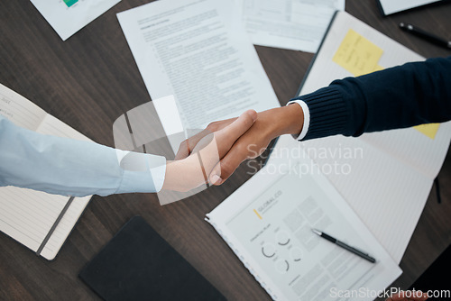 Image of Business, hands and handshake with documents above paperwork for employment agreement or analysis at the office. Hand of people in partnership shaking for corporate contract, welcome or b2b meeting