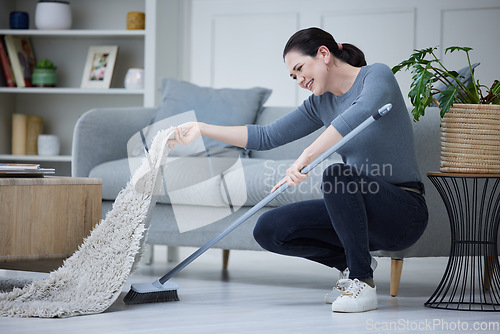 Image of Woman, cleaning home and with broom sweeping carpet for daily chores, cleanliness and doing housework. Cleaner, domestic and lady complete duties, clean under mat for dust, health and hygiene