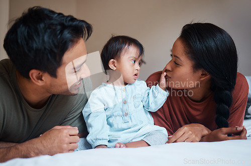 Image of Family, parents and Down syndrome baby with love, care for relaxing and spending quality time together at home. Mother and father relax on bed playing with new born child with genetic disorder