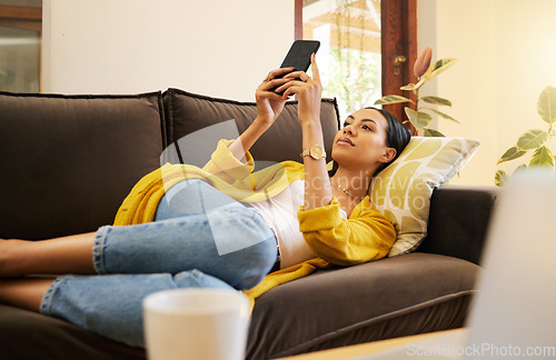 Image of Relax woman on her phone with social media while on the sofa in house. Content female browsing internet with app while relaxing on the couch at home reading news, post and internet or web