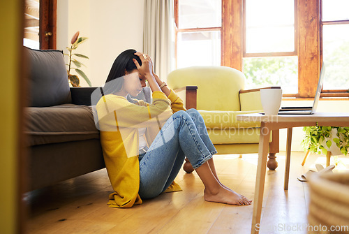 Image of Stressed woman, depression and lonely in the living room sitting on the floor at home. Young sad female suffering from mental health issues and anxiety or headache in apartment or house