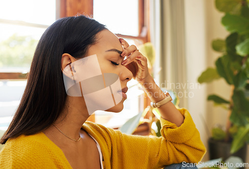 Image of Stressed woman, headache and burnout with mental health issues at home in the living room. Female in depression alone holding head feeling anxious, depressed and frustrated at the house