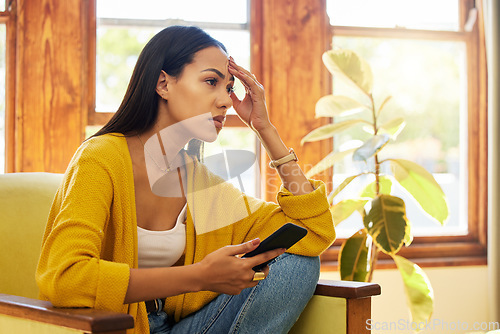 Image of Stress, tired and woman with headache on phone sitting on chair in the living room of her home. Bad news, burnout and frustrated girl from Colombia scrolling on social media with smartphone in lounge