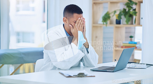 Image of Covid doctor, tired in office from stress and face mask in hand after writing report on laptop with patient information documents. Coronavirus, medical professional burnout and exhausted from covid19