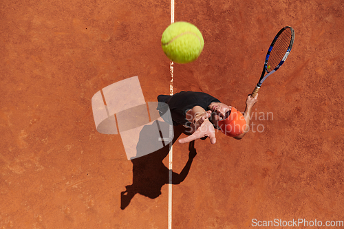 Image of Top view of a professional tennis player serves the tennis ball on the court with precision and power