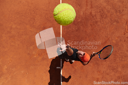 Image of Top view of a professional tennis player serves the tennis ball on the court with precision and power