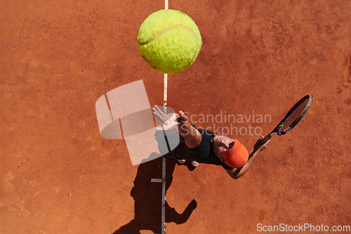 Image of Top view of a professional tennis player serves the tennis ball on the court with precision and power