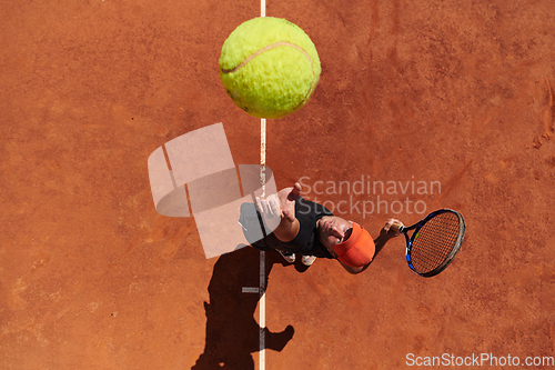 Image of Top view of a professional tennis player serves the tennis ball on the court with precision and power