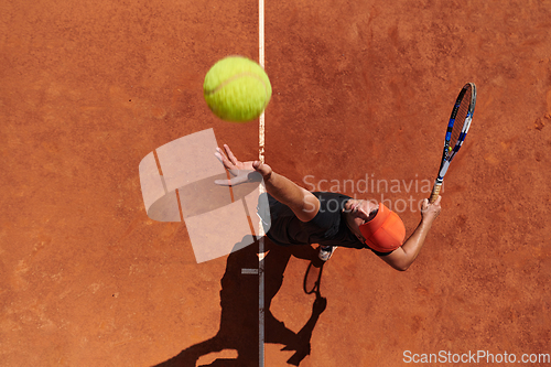 Image of Top view of a professional tennis player serves the tennis ball on the court with precision and power