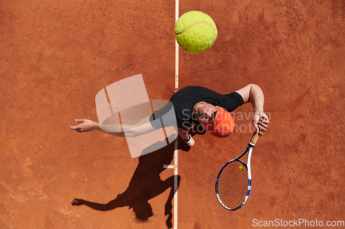 Image of Top view of a professional tennis player serves the tennis ball on the court with precision and power