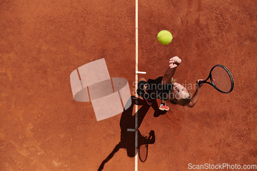 Image of Top view of a professional female tennis player serves the tennis ball on the court with precision and power