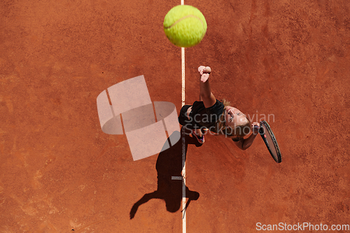 Image of Top view of a professional female tennis player serves the tennis ball on the court with precision and power