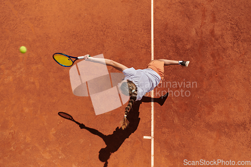 Image of Top view of a professional female tennis player serves the tennis ball on the court with precision and power