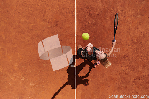 Image of Top view of a professional female tennis player serves the tennis ball on the court with precision and power