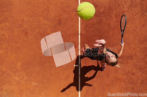 Image of Top view of a professional female tennis player serves the tennis ball on the court with precision and power