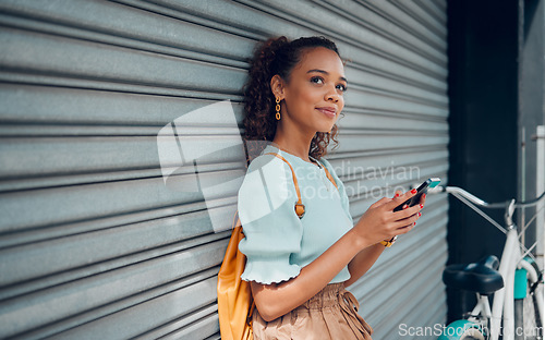 Image of City lifestyle, girl with phone and bike standing at wall thinking before writing text. Happy female student, bicycle and smartphone outside street, communication, 5g and sustainable urban transport.