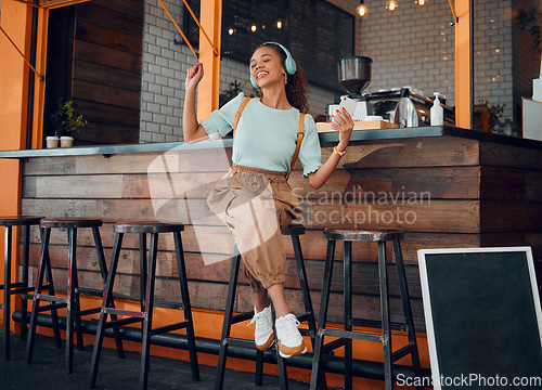 Image of Coffee shop, headphones and woman listening to music on smartphone for customer service experience and happy with wifi in cafe. Happy gen z girl or student relax in a restaurant using phone and audio