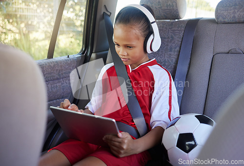 Image of Tablet, sports and relax child on car travel transportation to soccer, football or match game in SUV van with safety seat belt. Youth girl streaming video, subscription movie or use kid friendly app