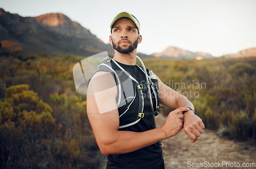 Image of Fitness, man and smart watch time for mountain running, exercise workout or healthy hiking trail training. Focus runner monitor stopwatch, check steps and cardio progress for wellness goals in nature