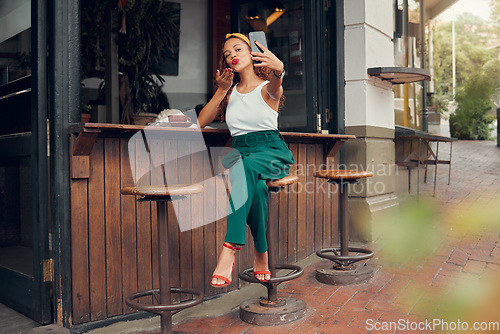 Image of Restaurant, woman and influencer taking a phone selfie for social media content for online followers outdoors. Lifestyle, cafe and young person blowing a kiss on a photo enjoying summer holidays