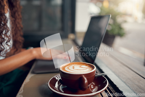 Image of Coffee, laptop and business owner working, planning and typing on internet at a coffee shop. Remote worker with a cappuccino at a cafe or restaurant for wifi connection to work online with a computer