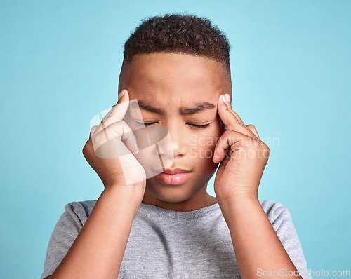 Image of Child with headache, stress and mental health problem or fatigue pain on blue studio background. Frustrated african american kid, depressed boy and angry youth with fingers massaging temples of head