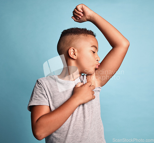 Image of Children, bicep and kiss with a boy bodybuilder in studio on a blue background for fitness, health or wellness. Sports, strong and kids with a young male child kissing his arm muscle during training