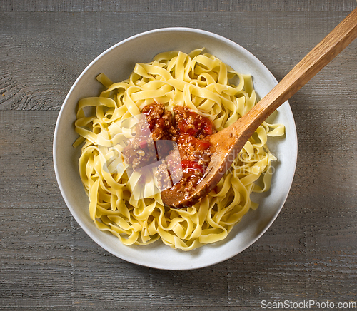 Image of bologna sauce is added to a bowl of pasta