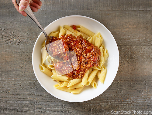 Image of bologna sauce is added to a bowl of pasta