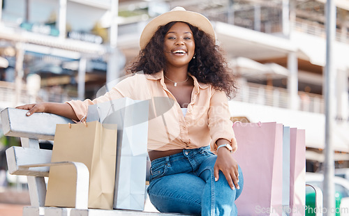 Image of Black woman, retail shopping bag and outdoor bench break from travel buying, sales and summer market retail fashion promotions in San Francisco California. Happy portrait of wealthy customer spending