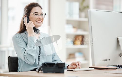 Image of Telephone, computer and business woman in office, talking or conversation. Landline, receptionist and happy female from Canada in phone call, discussion or work call on desk in company workplace.