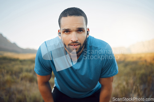 Image of Portrait of tired runner, music for motivation on earphones and man taking a break from a nature fitness run. Running for exercise, cardio health workout and enjoy freedom of sport training in nature