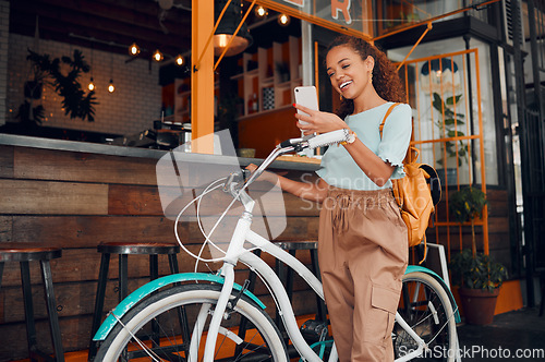 Image of Woman, happy and bike with phone at cafe on travel in city with bag. Black woman, smartphone and smile for communication, meme or social media on app with bicycle at coffee shop in San Francisco