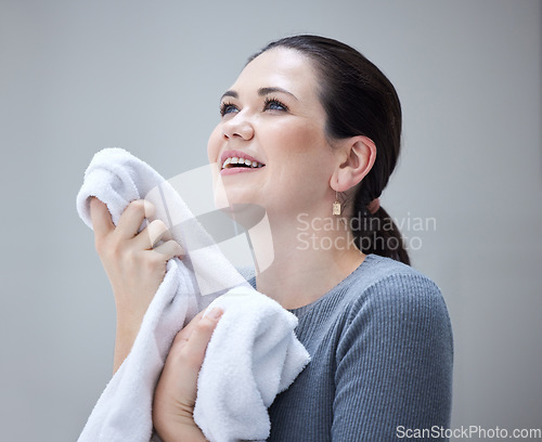 Image of House work, laundry and woman holding towel and enjoying fresh smell of fabric detergent for housekeeping against a grey background. Smile of female cleaning and doing washing or laundry in Ukraine