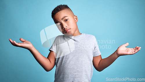 Image of .Doubt, question and shrug from child with confused facial expression, dont know gesture and raised hands. Young boy, African youth and face portrait of puzzled black kid isolated on blue background.