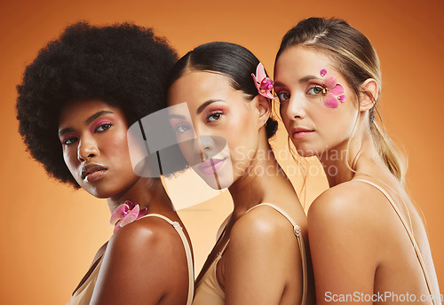 Image of Skincare, flowers and beauty portrait of women in studio for feminism, woman empowerment and cosmetics. Diversity, face and group of beautiful natural models with floral standing by orange background