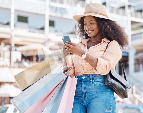 Image of Black woman, retail shopping bag and city smartphone search fashion sales, social media and online newsletter, discount code and store promotions. Wealthy customer using phone on ecommerce mobile app