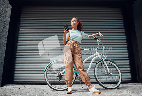 Image of Bicycle, phone and black woman in city, street or urban road outdoors. Bike, travel and happy female from South Africa on 5g mobile tech, internet browsing or social media, web or online surfing.