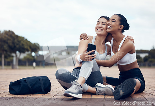 Image of Workout, happy and friends with phone on floor after fitness training in the city of New York together. Runner and black woman talking about funny 5g mobile app after health exercise outdoor