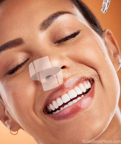 Image of Face, skincare and serum with a model black woman using antiaging treatment on her skin in studio on an orange background. Beauty, cosmetics and skin with a young female applying retinol for health