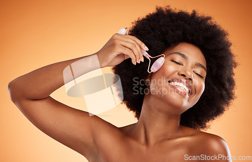 Image of Beauty, skincare and black woman with jade roller in studio, happy, smile and relax during grooming with mockup background. Face, product and wellness model enjoying facial massage with roller tool