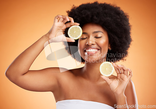 Image of Fruit, beauty and skin of a black woman with smile holding a lemon on her face in brown studio background. Happy afro female model in healthy, vitamin c and natural skincare wellness for healthcare